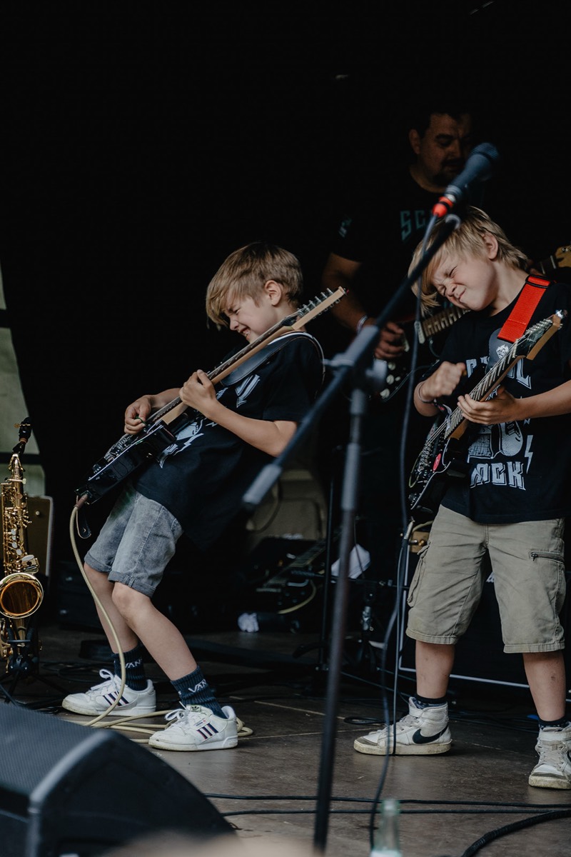 Zwei junge Gitarristen rocken mit geschlossenen Augen auf der Festivalbühne