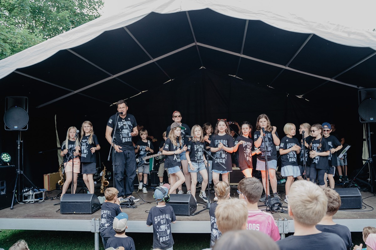 Die ganze Band mit Sänger auf der Festivalbühne unter dem Zeltdach
