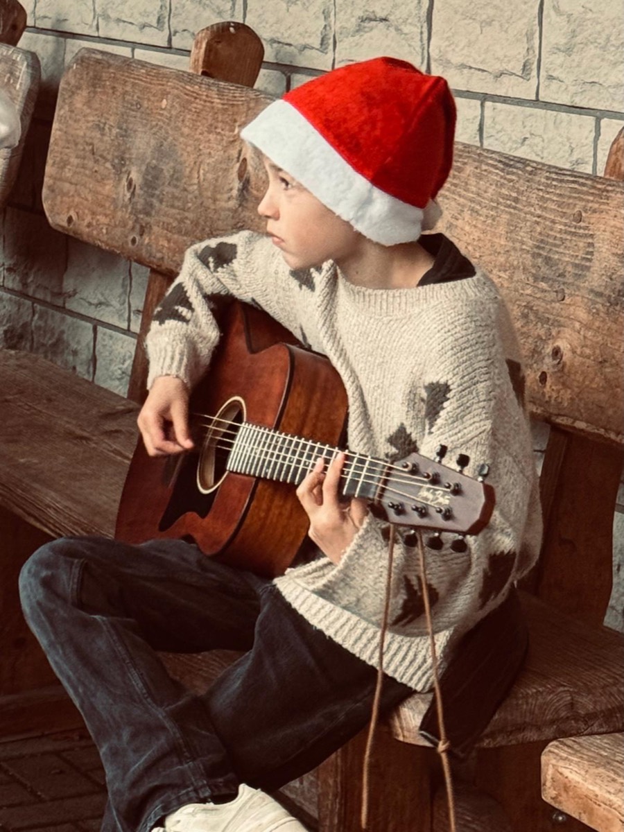 Junger Gitarrist mit Nikolausmütze spielt Akustikgitarre
