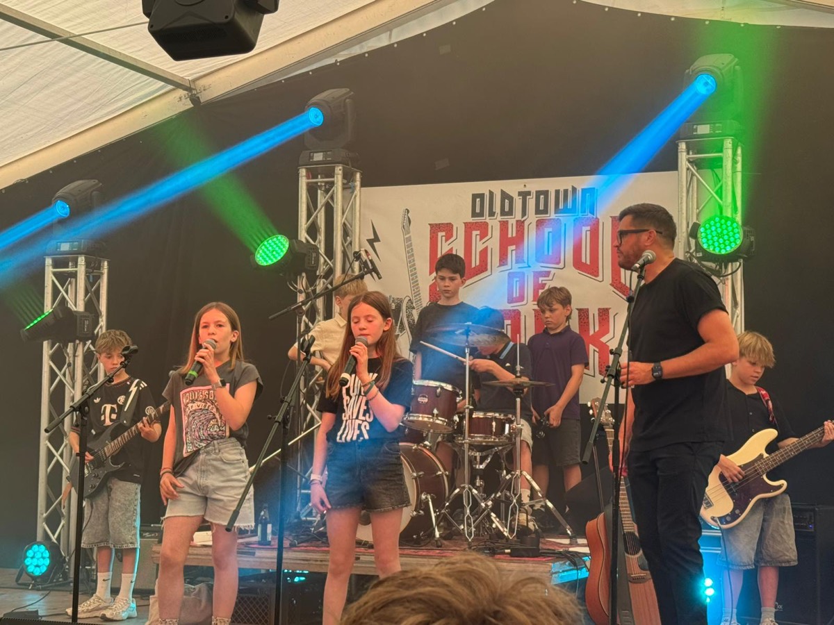 Zwei Sängerinnen vorne, dahinter Drums und Bass im bunten Bühnenlicht