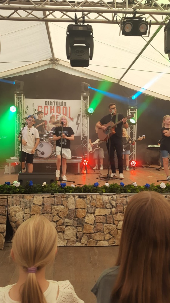 Die Band auf geschmückter Bühne, davor das Publikum